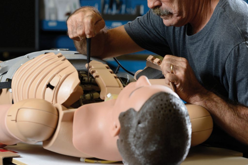 Homem fazendo manutenção preventiva em um simulador de paciente