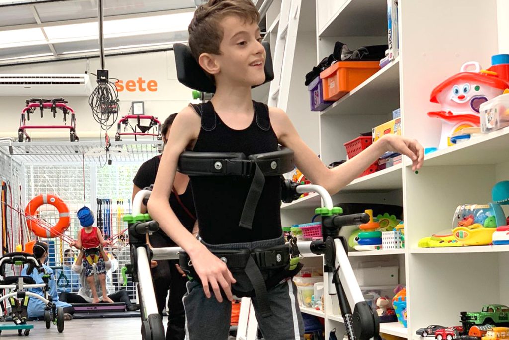 Criança com deficiência de pé com parapódium, indo pegar um brinquedo em uma clínica de terapias