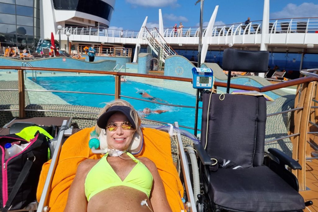 Foto de uma mulher loira de biquini verde claro sentada tomando sol em um navio