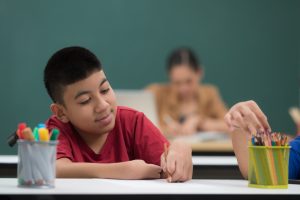 foto de um aluno com deficiência em uma sala de aula escrevendo