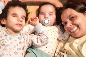 Mãe deitada na cama com seus dois filhos