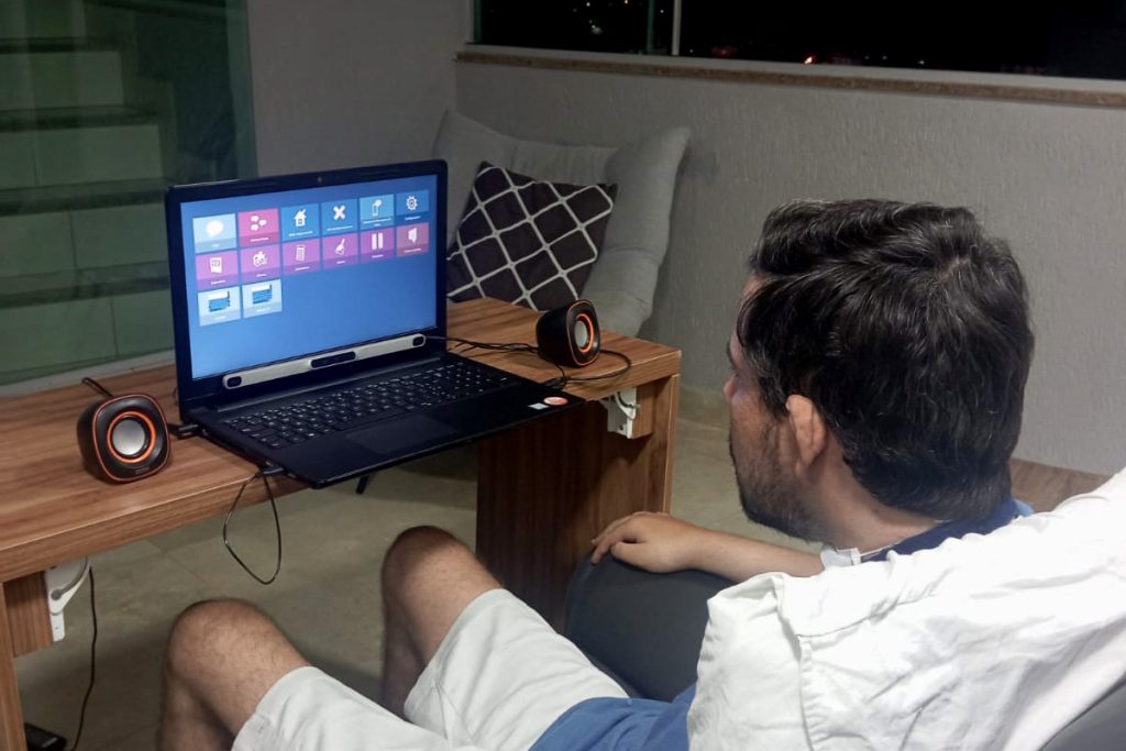 Foto de Andre utilizando na sala de sua casa o mouse ocular para acessar e controlar seu computador.