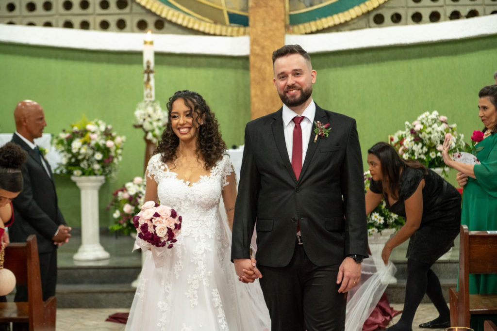 Foto de um casal jovem saindo do altar após o seu casamento.