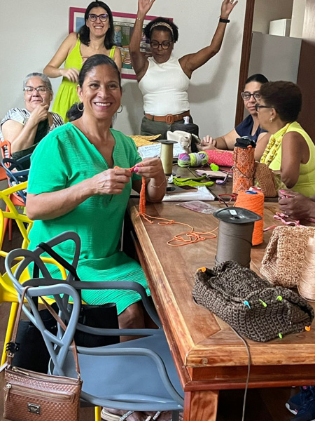 6 mães sentadas em uma mesa fazendo croche