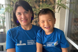 Foto de Priscila e seu filho Benjamin de 4 anos vestindo uma camiseta azul sobre o dia 15/2 - Dia Internacional da Síndrome de Angelman