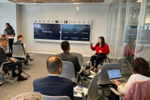 Foto de uma sala de reunião onde Carolina, uma mulher cadeirante está fazendo uma apresentação para diversos executivos