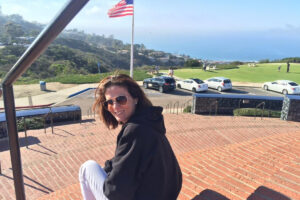 Foto de Giselle jovem sentada em uma escadaria no alto de uma praia da California