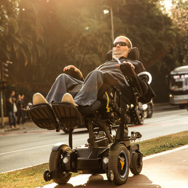 Foto de Rick sentado em sua cadeira motorizada passeando na ciclovia da avenida Paulista
