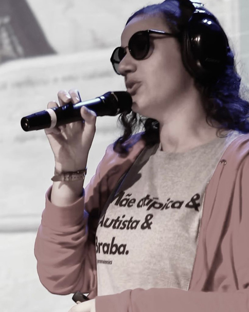 Foto de Fernanda com um microfone na mão dando uma palestra