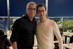 Foto de Geraldo e seu filho adotivo Mateus em um restaurante à noite.