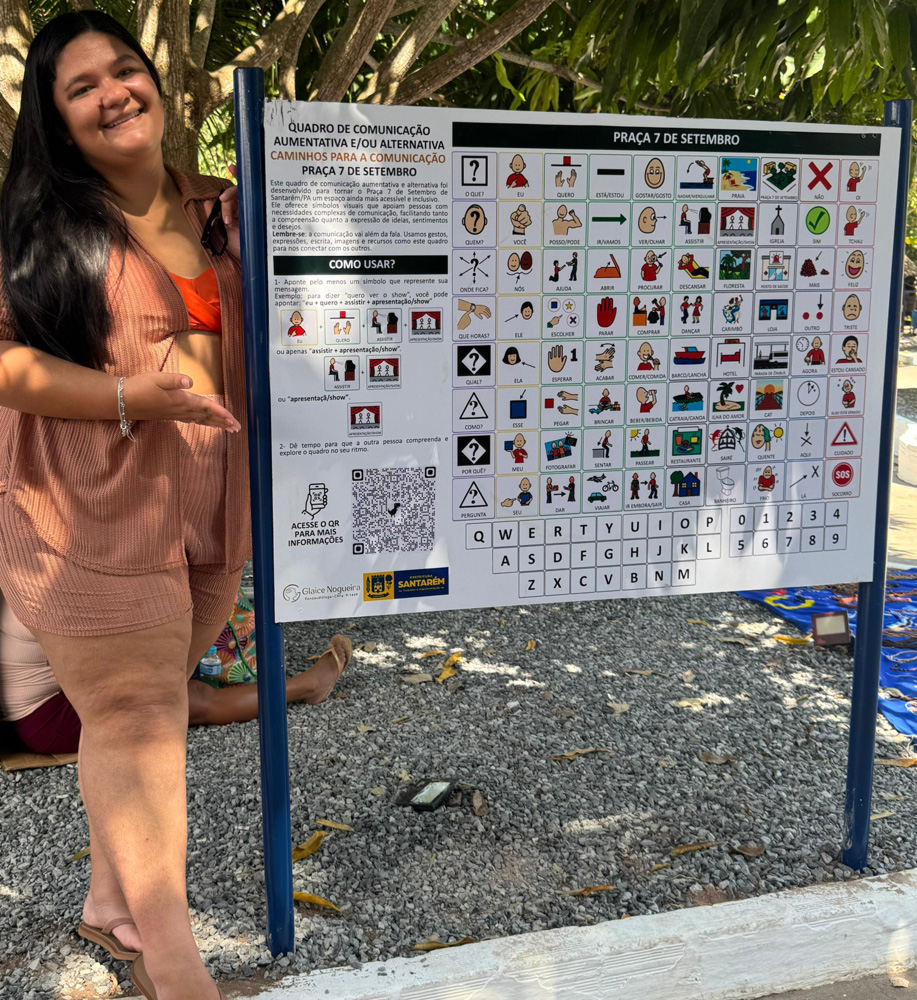 Foto de Glaice ao lado da placa de Comunicação Alternativa da Praça 7 de setembro.