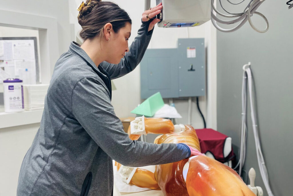 Foto de uma estudante, treinando fazer raio-x em um simulador tipo Phanton