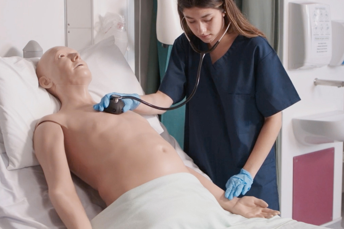 Foto de uma estudante treinando a diagnosticar a tuberculose em um manequim simulador.