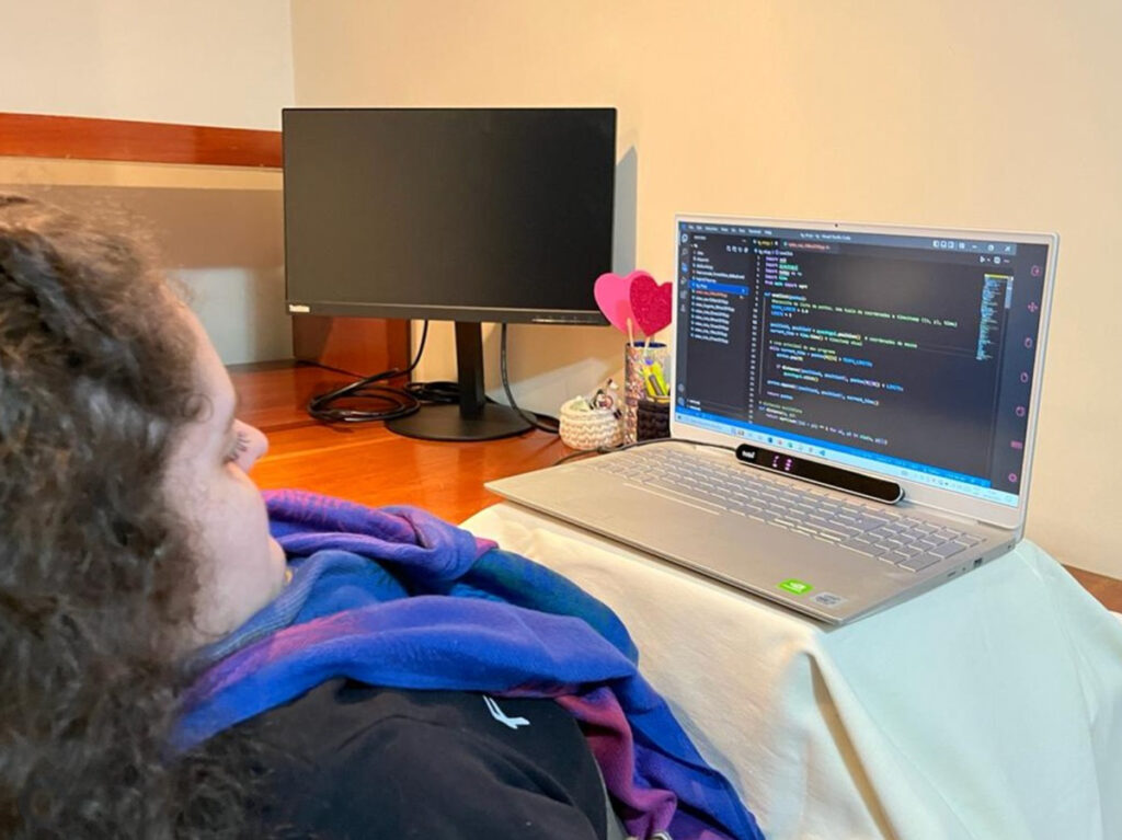 Foto de Julia trabalhando com a ajuda do rastreador ocular da Tobii.