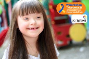 Foto de uma menina com síndrome de down sorrindo em um parquinho. Sobre a foto, logo do Workshop e da Abrapraxia