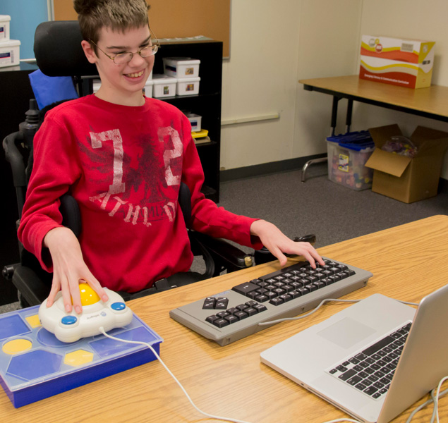 Foto de um garoto usando o computador com um mouse tipo trackball