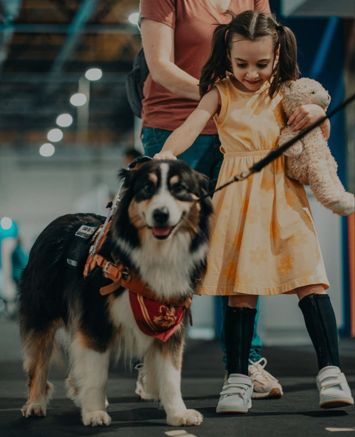 Foto de Julia andando com a ajuda do cão de assistência Léia. 