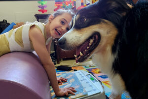 Foto de Júlia fazendo terapia ao lado de sua companheira canina Léia