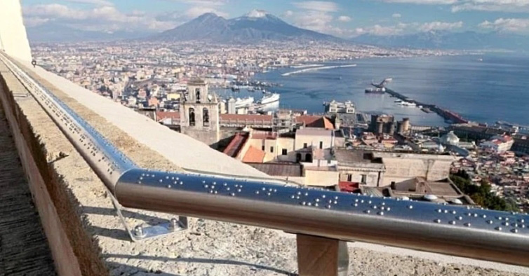 Foto da vista do Castelo Sant'Elmo com o corrimão em braille em primeiro plano.