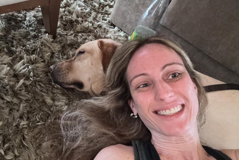 Foto de Juliana deitada no chão com a cabeça apoiada no seu labrador Quindim.