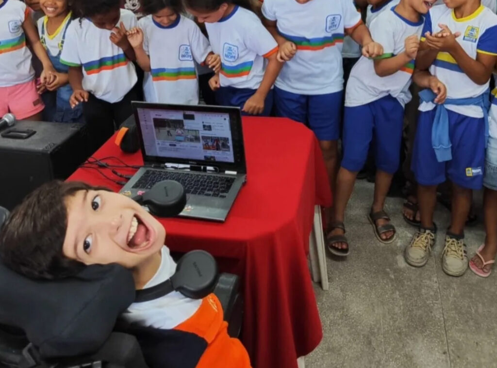 Foto de Pedro usando seu tablet com rastreador ocular para ser DJ para seus colegas de escola.