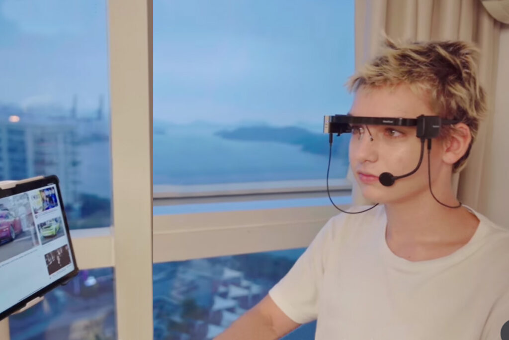 Jovem utilizando GlassOuse com acionador de bochecha para acessar o computador por meio de tecnologia assistiva.