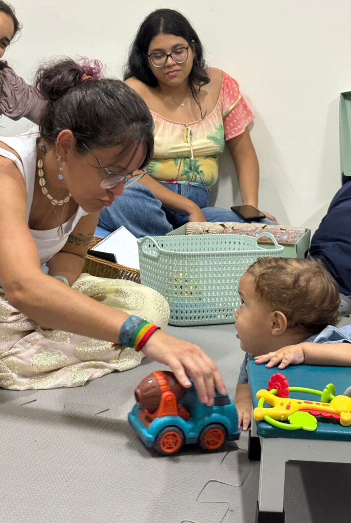 Foto de Dafne brincando com uma criança que olha interessada