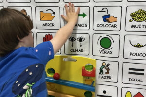 Foto de um menino usando um quadro de CAA para se comunicar enquanto brinca