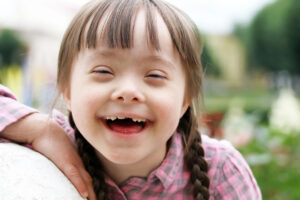Foto de uma garotinha com deficiencia intelectual e múltipla sorrindo