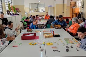 Grupo de pessoas idosas participando de atividades recreativas e de convivência em uma instituição, com jogos, artesanato e música.