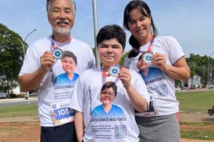 Gustavo com seu pai e sua mãe mostrando a medalha de uma corrida de consicentização.