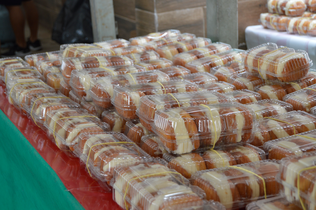 Diversas embalagens com sonhos organizadas sobre uma mesa para venda.