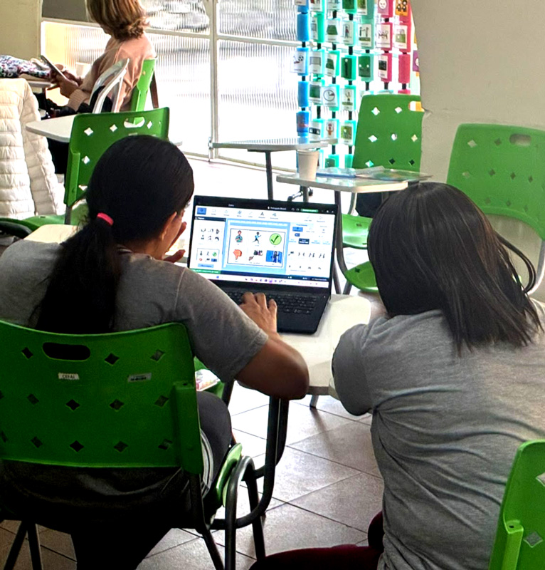 Profissionais da educação utilizam o software Boardmaker 7 em um notebook para criar materiais visuais de apoio à comunicação alternativa e à educação inclusiva.