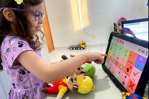 Adelina, criança autista que utiliza recursos de Comunicação Aumentativa e Alternativa como este tablet de CAA