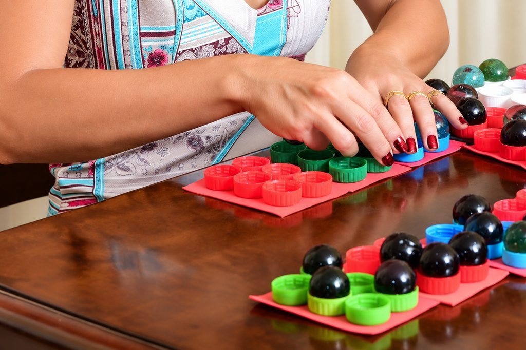 Mulher utiliza materiais táteis coloridos para atividades de alfabetização em Braille e estimulação sensorial, promovendo a aprendizagem e a autonomia de pessoas com deficiência visual.