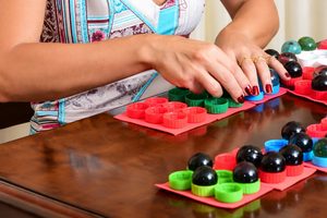 Mulher utiliza materiais táteis coloridos para atividades de alfabetização em Braille e estimulação sensorial, promovendo a aprendizagem e a autonomia de pessoas com deficiência visual.